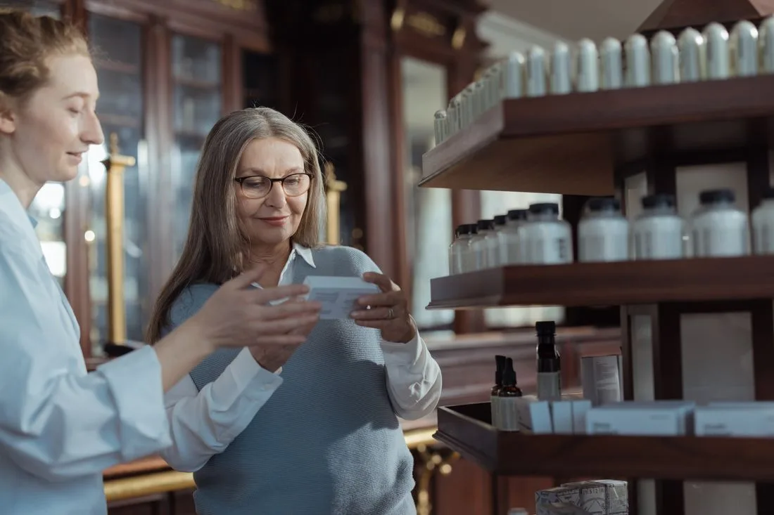 Interior de una farmacia con un farmaceutico atendiendo a una clienta
